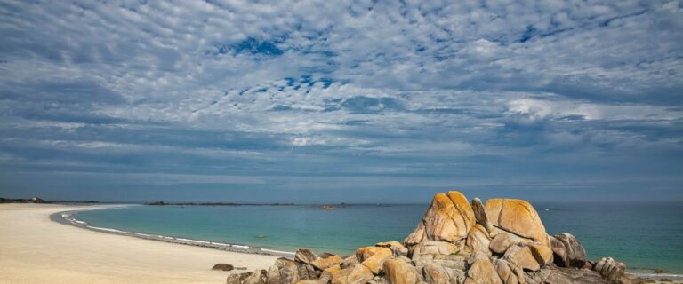 Beautiful sandy beach in Bretagne, France with striking rock formations and clear blue sea.